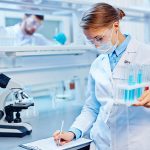 46624433 – young woman with flasks making notes in laboratory